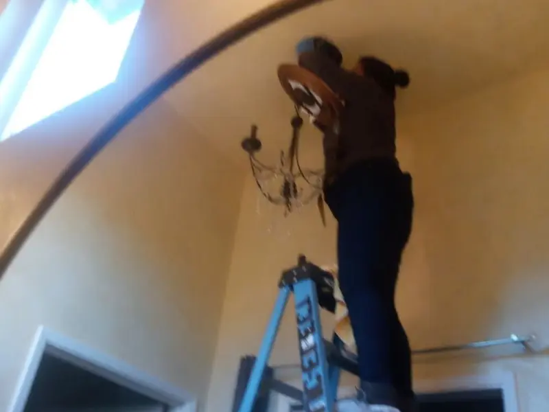 Electrician installing a chandelier in a Windsor residence